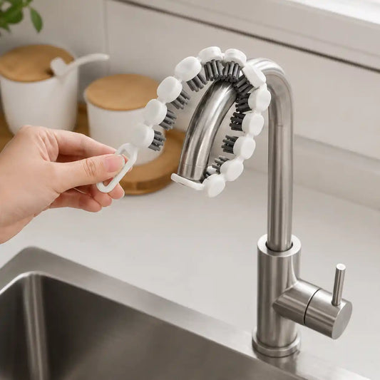 Lifestyle image showing a white flexible faucet cleaning brush wrapped around a stainless steel kitchen faucet to remove dirt and grease from hard-to-reach areas in a modern kitchen.